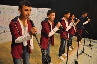 Jongens zingen op het podium tijdens de voorstelling One Thousand Questions van Kids for Kids